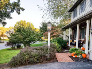 A front porch with an antique lamppost in front of it