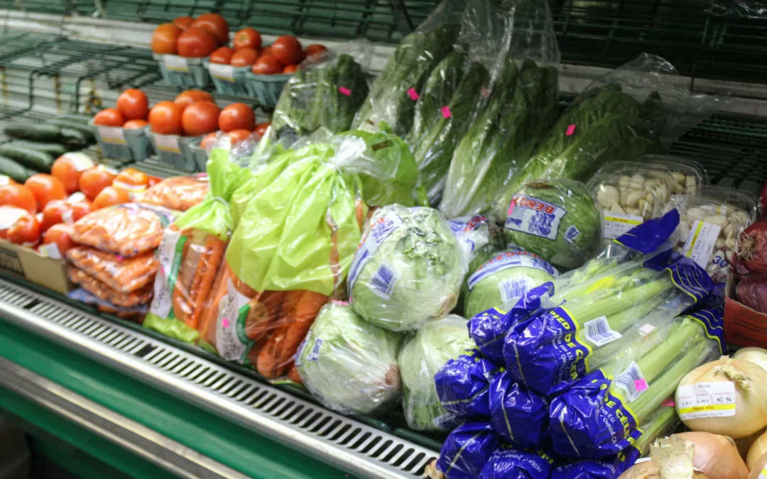 2.27.21-Leids-Market-Gallery-1-1-scaled-1 A grocery store produce section with packaged carrots, lettuce, celery, tomatoes, mushrooms, and cucumbers arranged on a refrigerated shelf.
