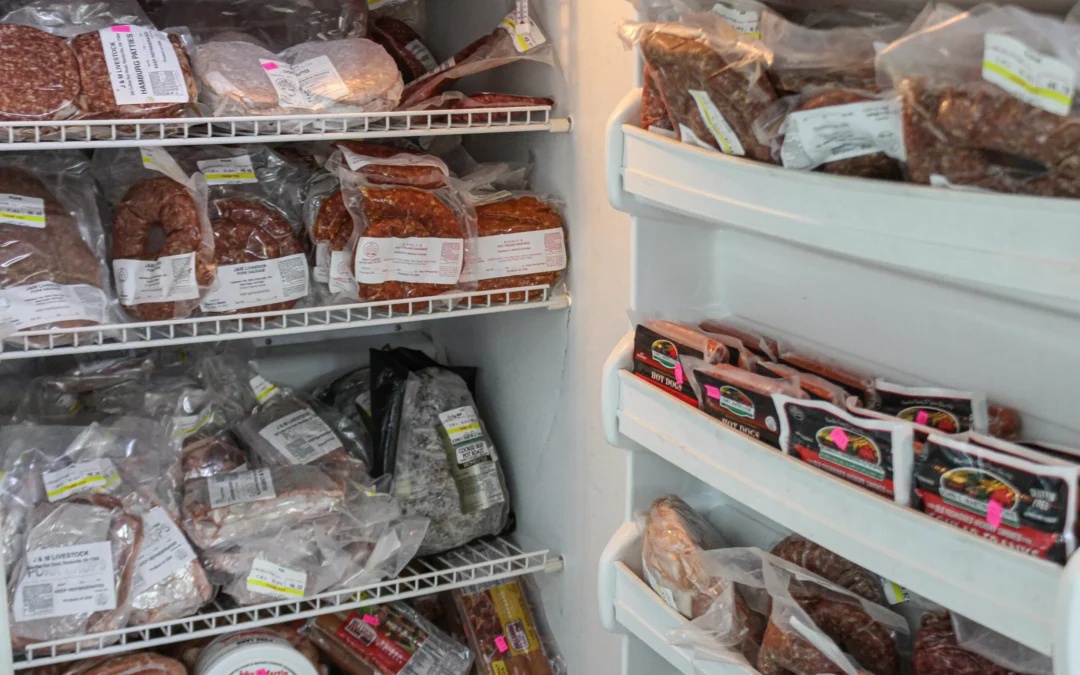 2.27.21-Leids-Market-Gallery-1-5-scaled-1 Shelves and door of a freezer filled with assorted vacuum-sealed packages of meat products, including sausages and ground meat.