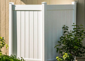 A white vinyl shower enclosure in front of a house.