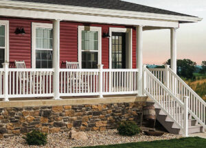 A red house with a white vinyl porch and stair railing.