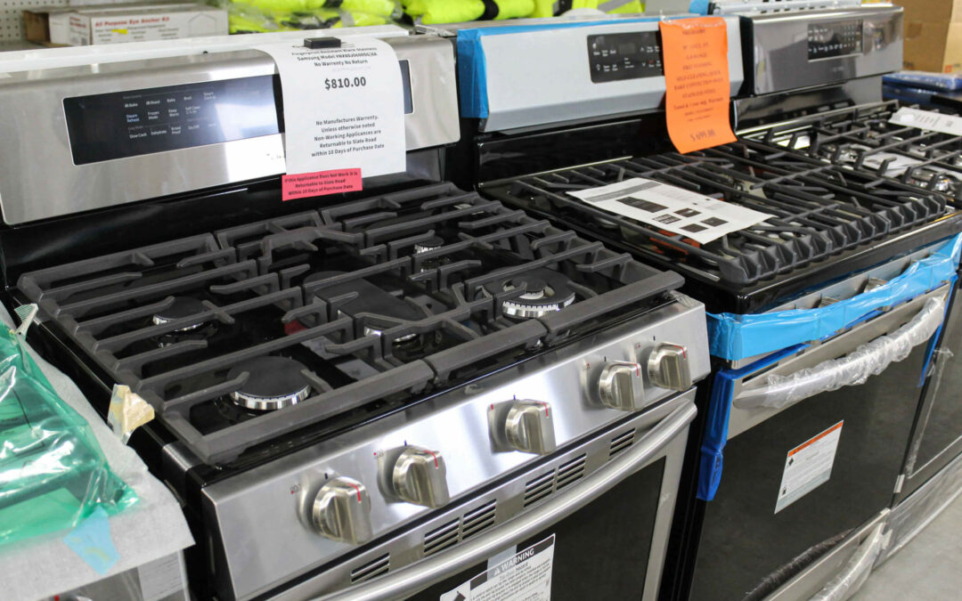 Slate Road Supply Ephrata PA A row of new stainless steel gas ranges with price tags displayed in an appliance store.