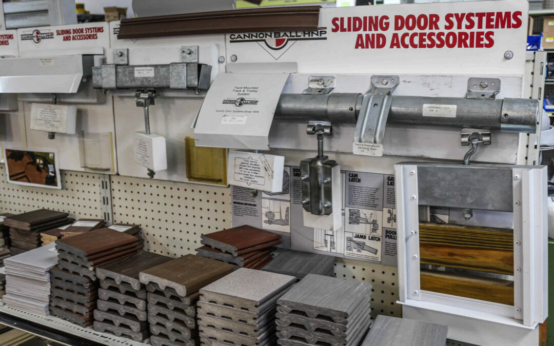 Slate Road Supply Ephrata PA Display of sliding door systems and accessories on shelves in a hardware store, including tracks, handles, and sample materials.