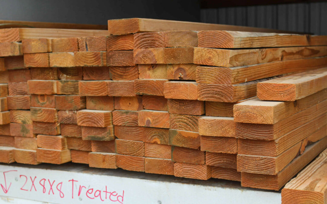 Slate Road Supply Ephrata PA Stacks of freshly cut and treated wooden planks on a platform, with markings indicating their size and treatment.