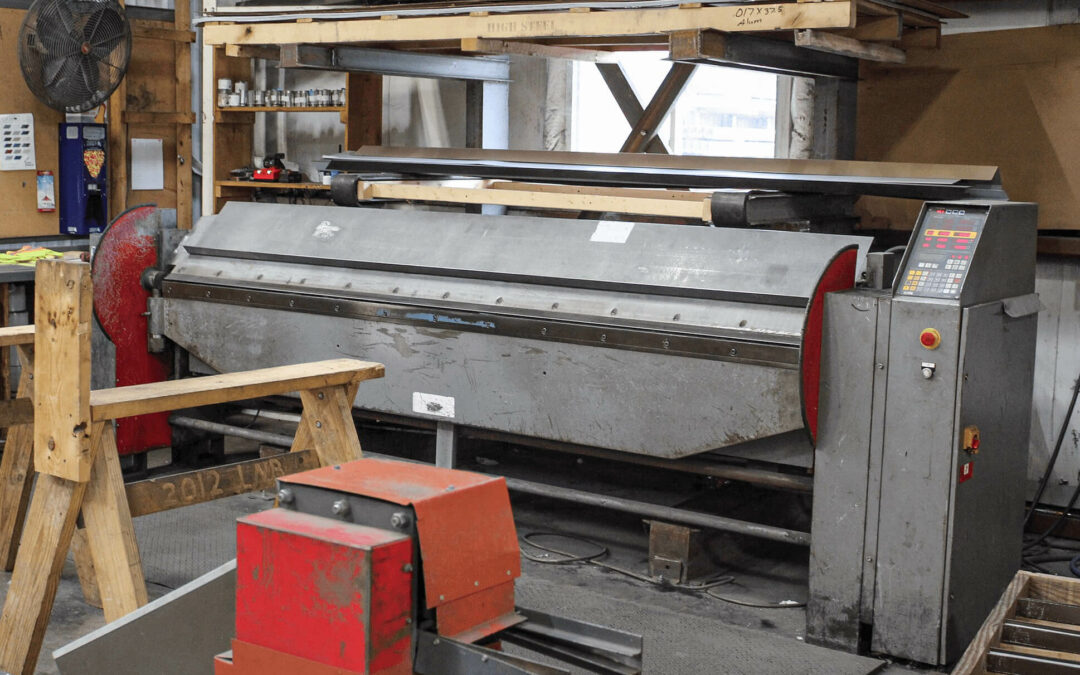Slate Road Supply Ephrata PA Large industrial sheet metal brake machine in a workshop with tools and storage shelves in the background.