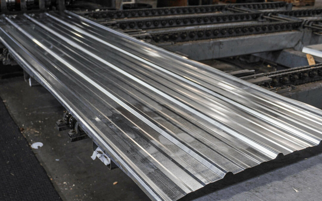 Slate Road Supply Ephrata PA Stack of long, shiny metal sheets with corrugated profiles, stored in an industrial setting.