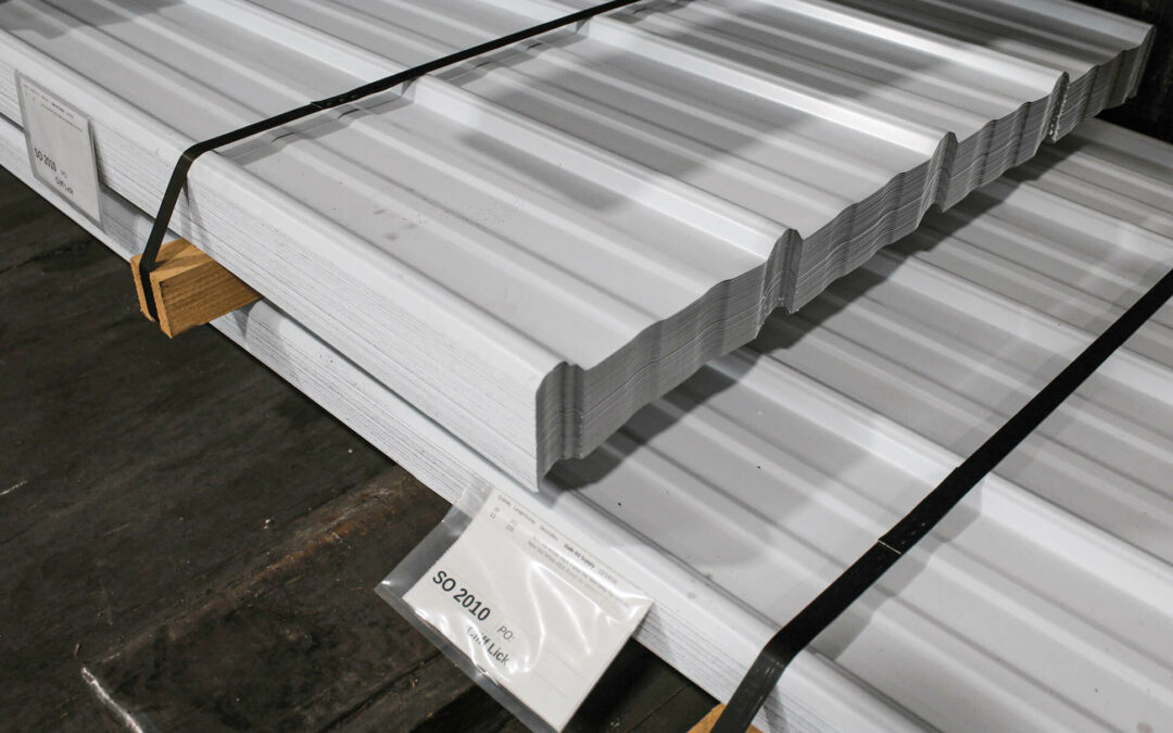 Slate Road Supply Ephrata PA Stacks of metal roofing sheets secured with straps, placed on wooden pallets in a warehouse.