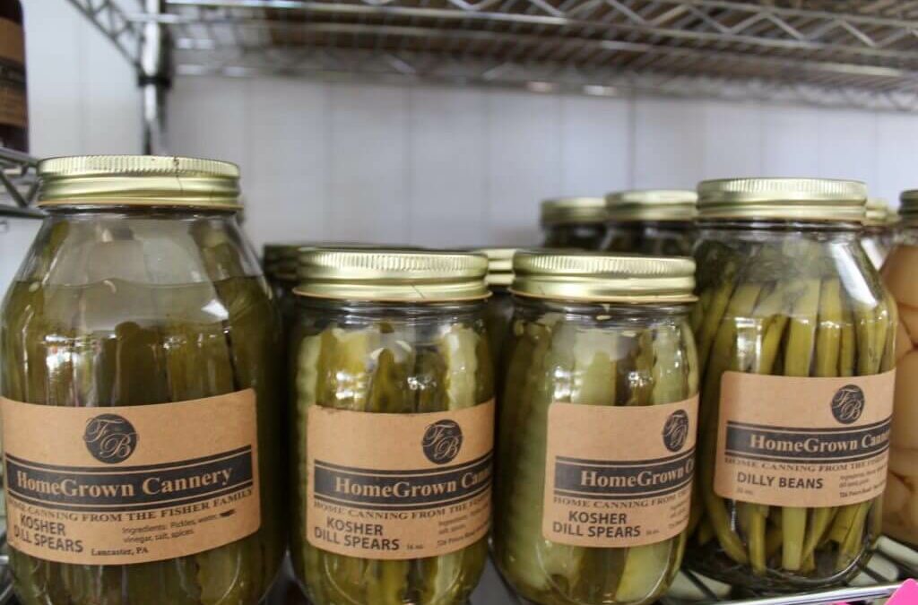 Homegrown Cannery Stand New Holland PA Jars of HomeGrown Cannery products on a shelf, including Kosher Dill Spears and Dilly Beans, with gold lids and brown labels.