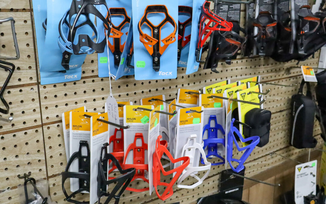 Weaver's Bike Shop Ephrata PA A display of various bike bottle cages in different colors and brands hanging on a pegboard in a store.