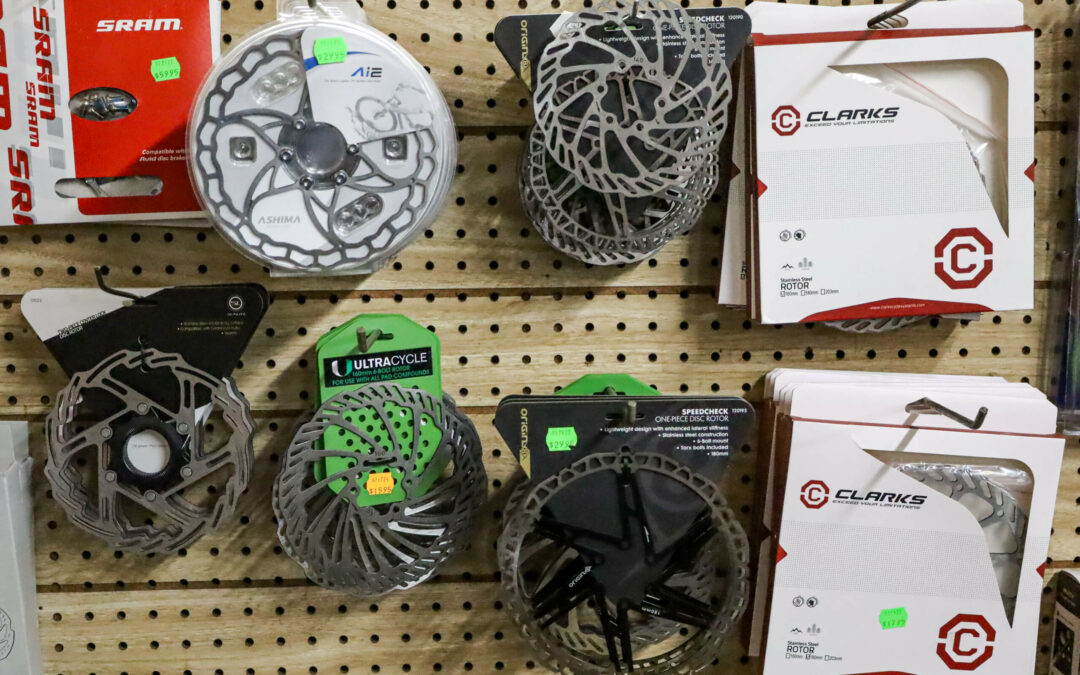 Weaver's Bike Shop Ephrata PA Display of various bicycle brake discs and rotors from different brands, hanging on a pegboard wall in a store.