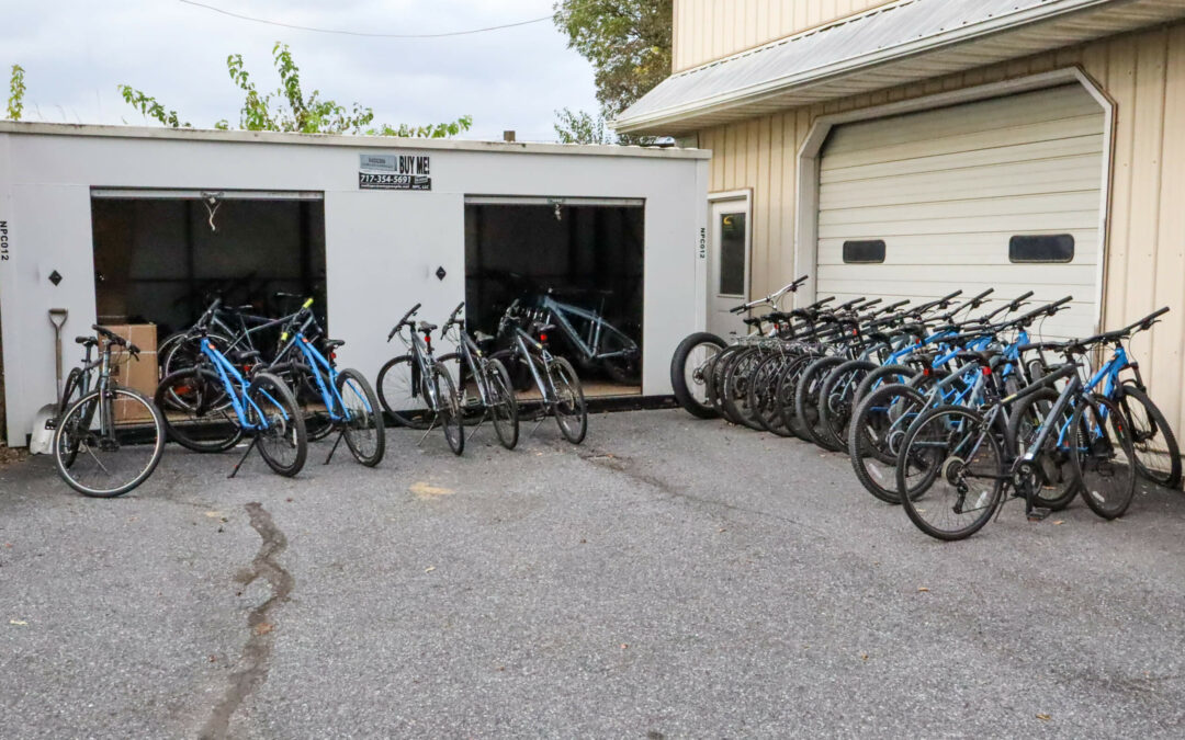 Weaver's Bike Shop Ephrata PA A storage area with multiple bicycles parked outside and inside two open garages, next to a large garage door on the right.