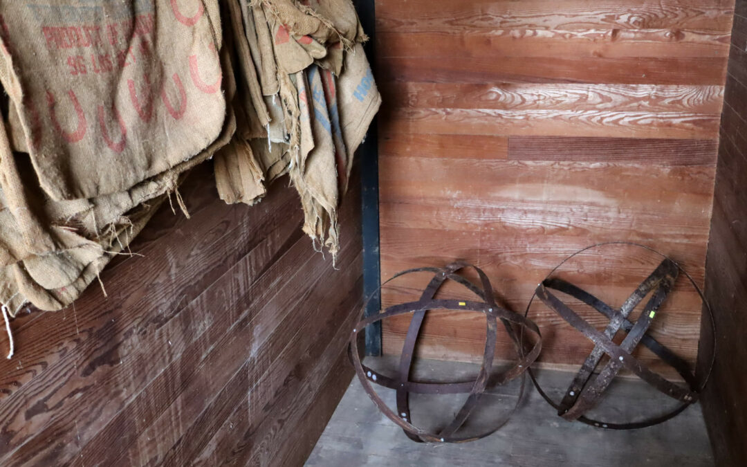 Pine Hill Farms Lititz PA A wooden room with burlap sacks hanging on the left wall and two metal spherical objects resting on the floor on the right.
