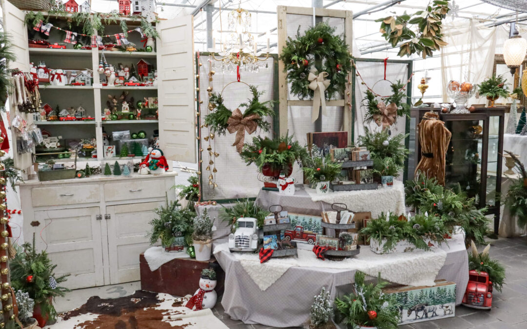 Reiff's Farm Market Ephrata PA A festive holiday display with wreaths, ornaments, and decorations arranged on shelves and tables, featuring greenery, snowmen, trucks, and farmhouse-themed accents.