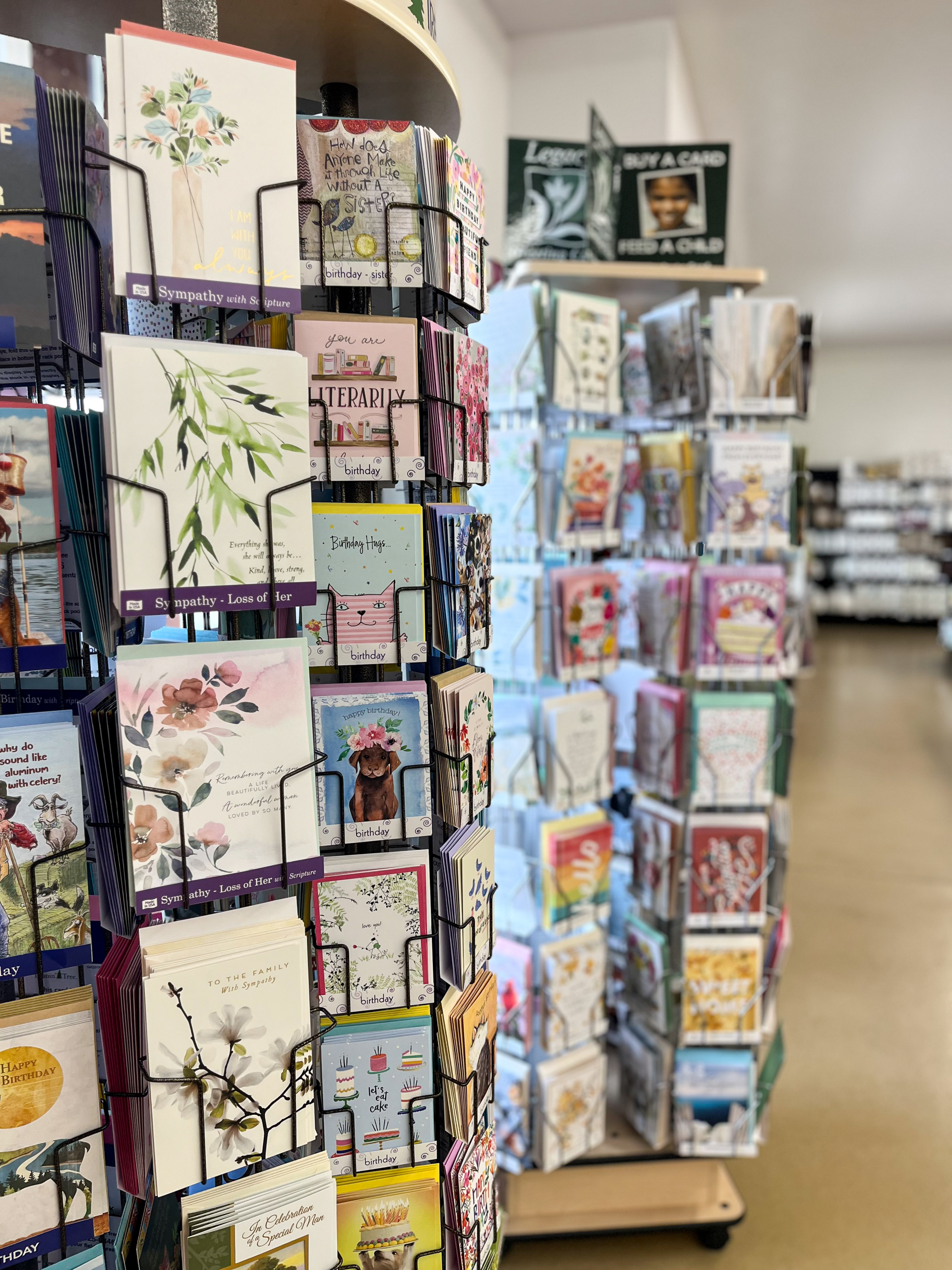 The Country Store Mount Joy PA Display racks in a store filled with assorted greeting cards, including sympathy, birthday, and congratulatory messages, arranged in vertical rows.
