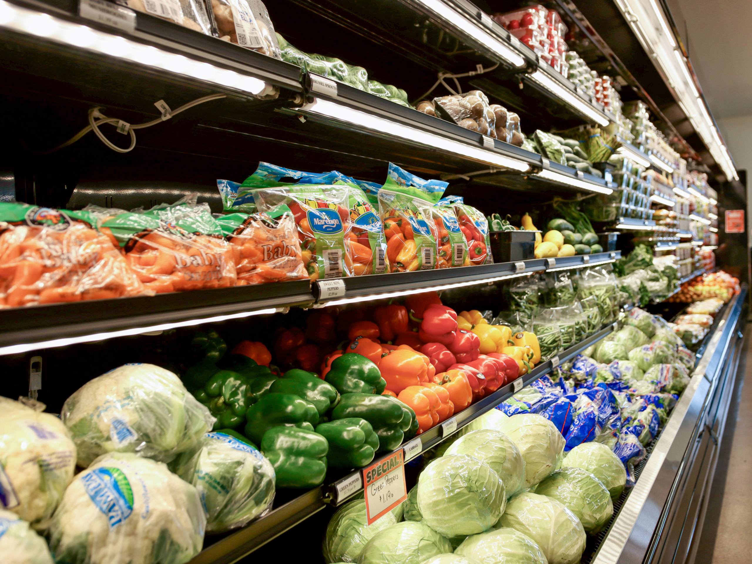 The Country Store Mount Joy PA Shelves in a grocery store produce section display bags of carrots, bell peppers, lettuce, and other fresh vegetables.