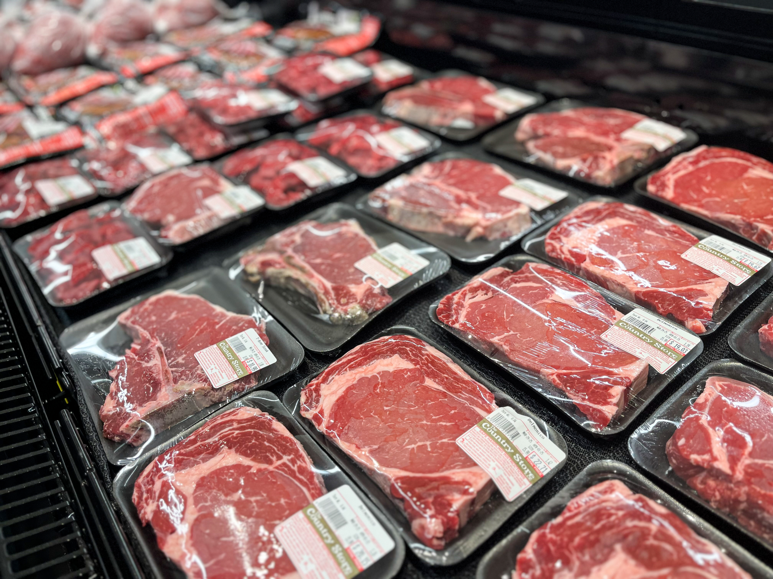 The Country Store Mount Joy PA Several packages of raw beef cuts are displayed on a grocery store shelf, each sealed in plastic with white labels.