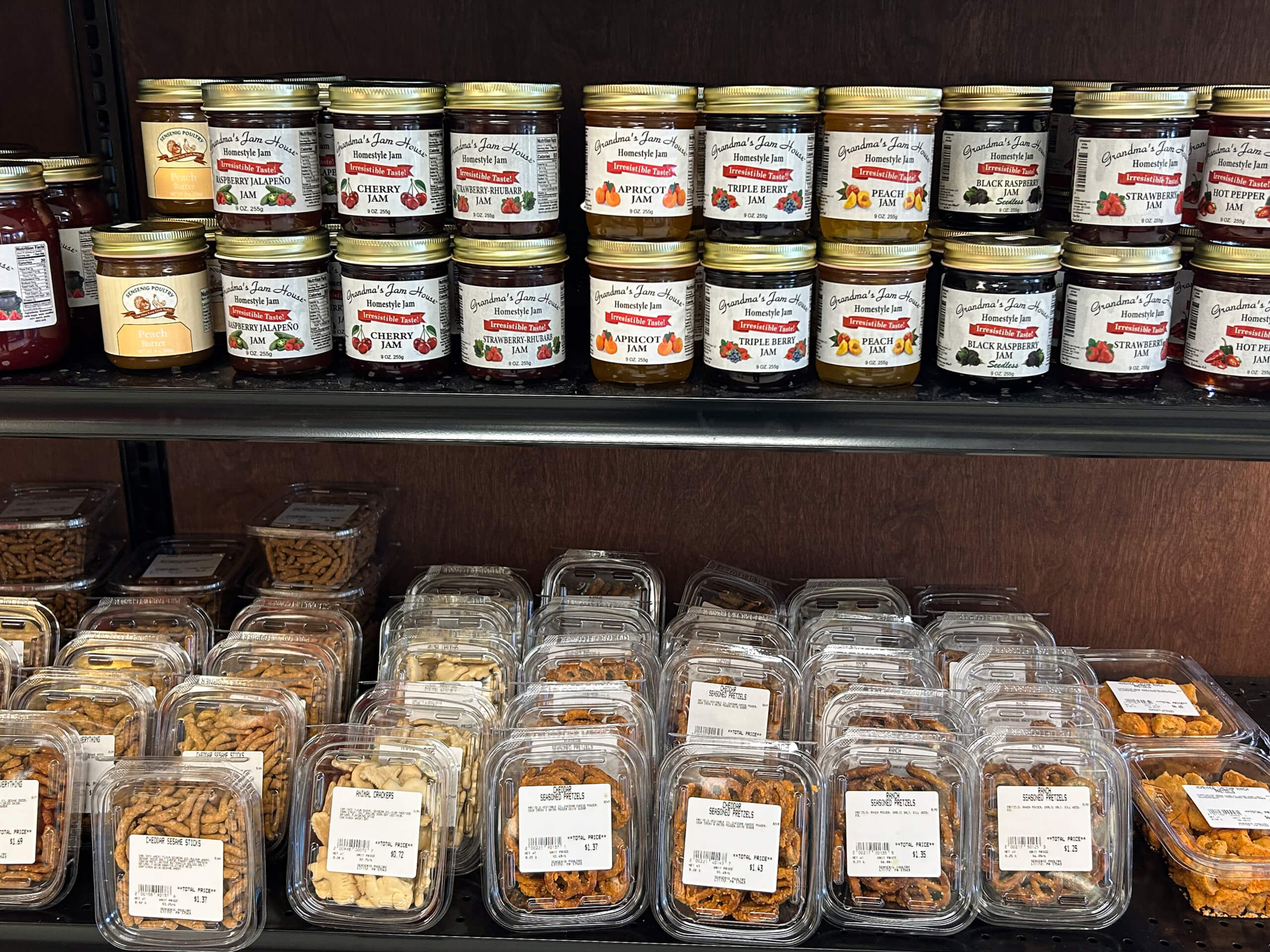 Sensenig Poultry Lititz PA Shelves display jars of preserves and spreads on the top rows, with plastic containers of assorted nuts and dried fruits on the lower rows.