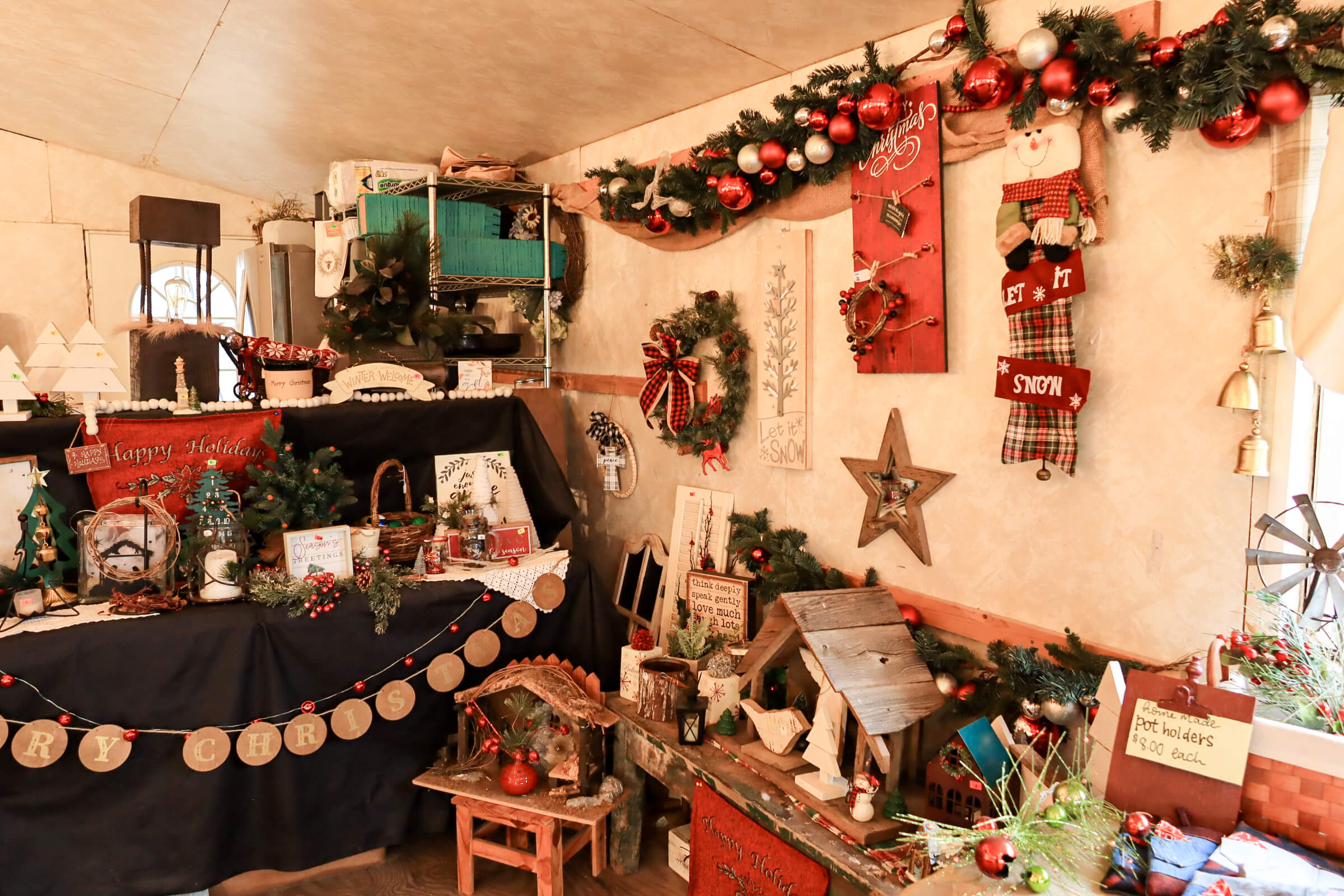 Busy Bee's Farm Market Ronks PA A room decorated for Christmas with garlands, stockings, wreaths, holiday signs, and various festive ornaments arranged on shelves and tables.