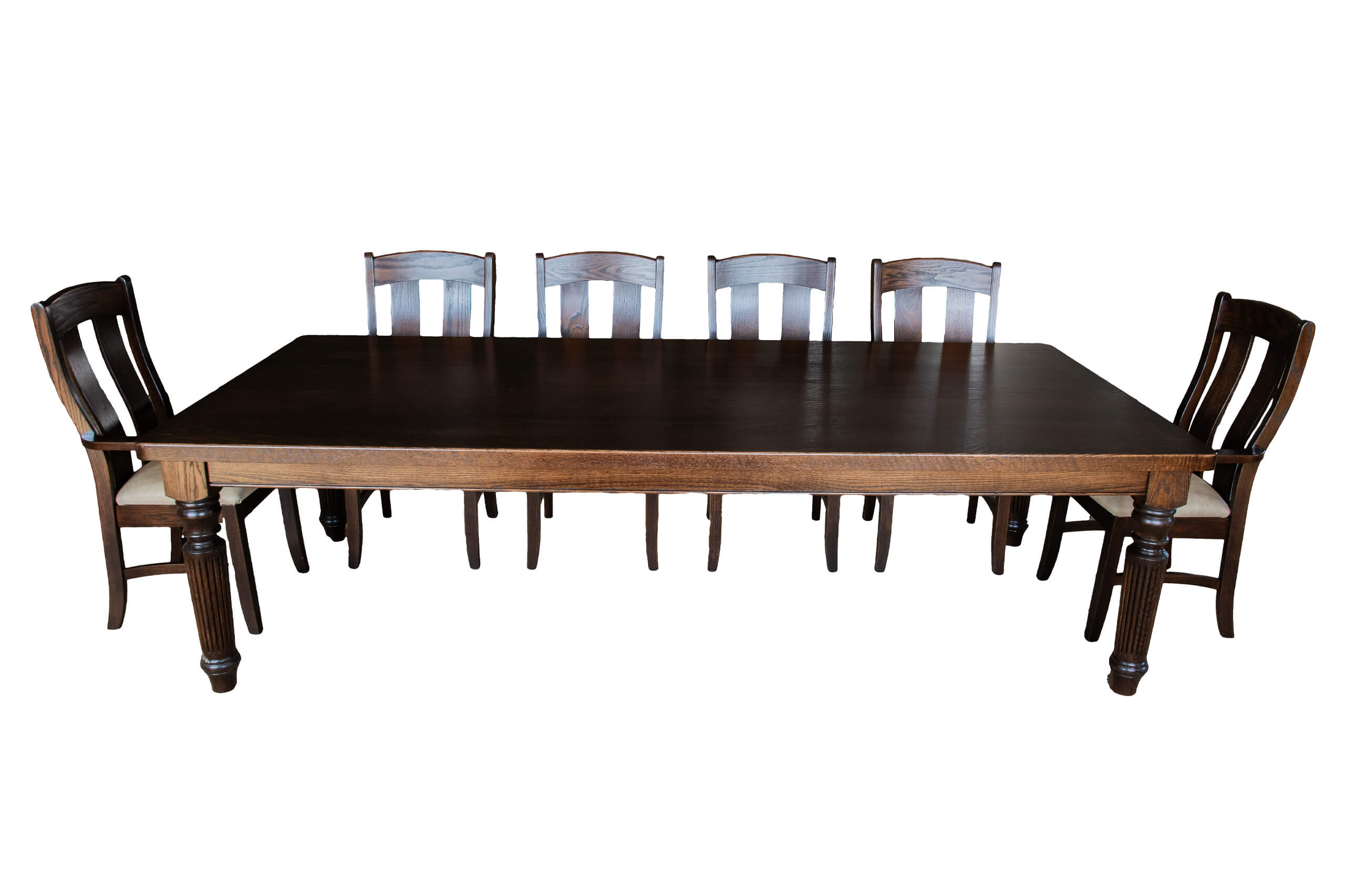 7.8.26 Spring Valley Woodworking Tables Gallery 3 A dark wooden dining table with six matching chairs, three on each side. The chairs have light-colored cushioned seats and carved backrests. The furniture is shown on a white background.