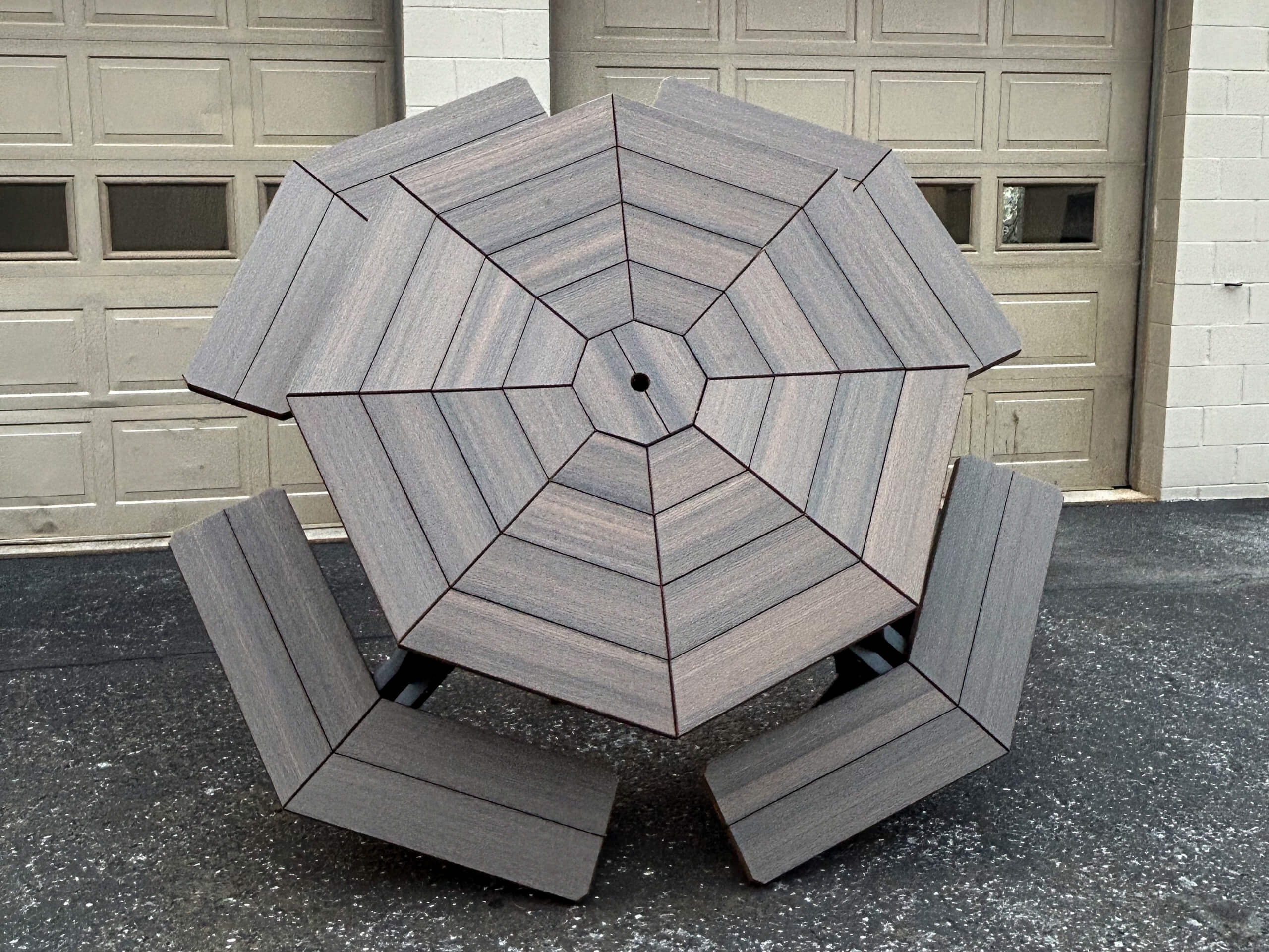 Oregan Lawn Furniture Leola, Pa Octagonal picnic table with matching attached benches is placed outdoors on a paved surface in front of beige garage doors.