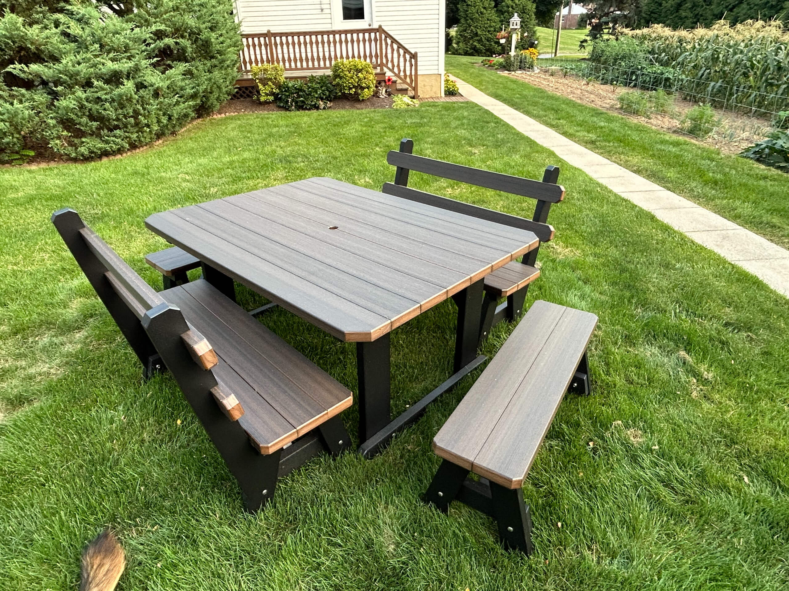 Oregan Lawn Furniture Leola, Pa Rectangular outdoor picnic table with four matching benches on green grass near a walkway, shrubbery, and a house in the background.