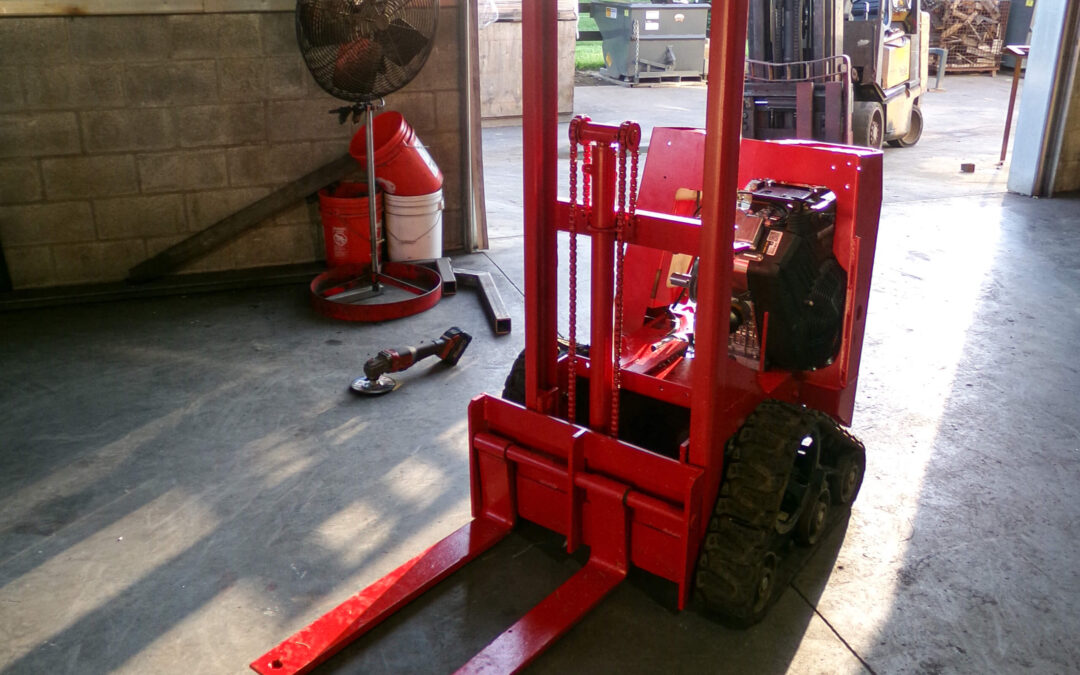 9.9.26 Nickel Mine Welding Gallery 1-1 A small red forklift with tracks is parked inside a warehouse near a wall, with a fan and tools visible in the background.