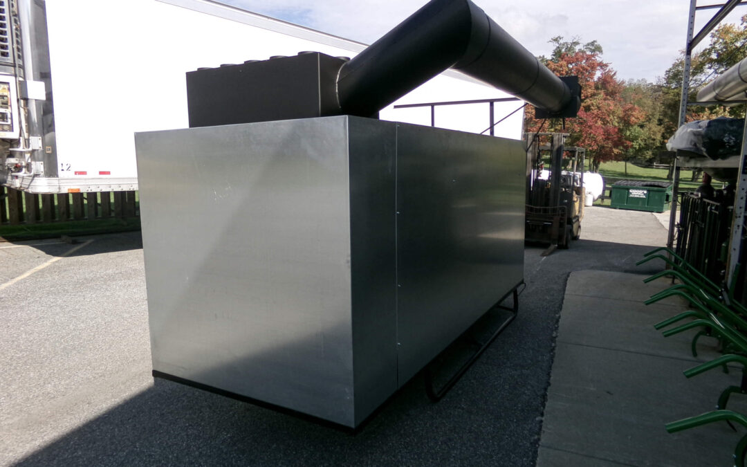 9.9.26 Nickel Mine Welding Gallery 1-10 Large metallic rectangular industrial unit with a black ventilation duct on top, positioned outdoors near a truck and fork lift on a paved area.