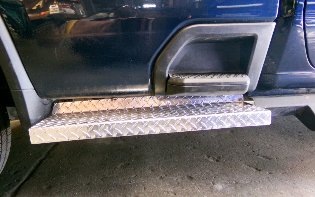 9.9.26 Nickel Mine Welding Gallery 2-7 A close-up of a vehicle’s side, showing a metallic diamond plate running board below the door and a step, all set against a concrete floor.