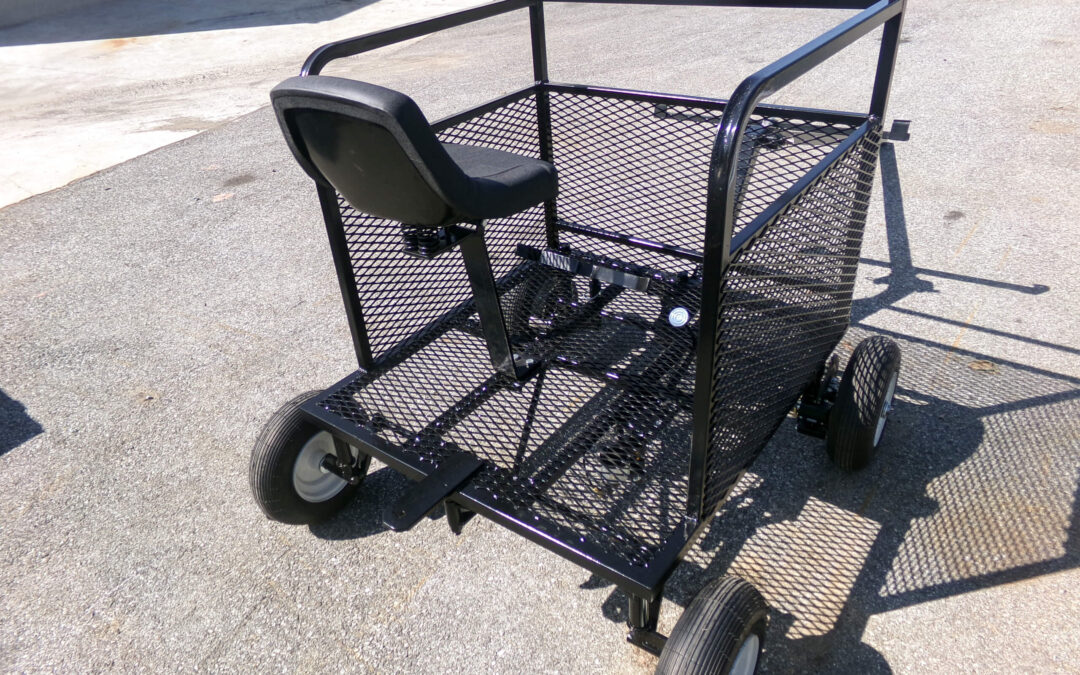 9.9.26 Nickel Mine Welding Gallery 2-9 A metal utility cart with mesh sides and a single seat is positioned outdoors on a paved surface under direct sunlight.